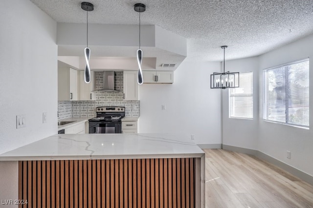 kitchen featuring white cabinetry, wall chimney exhaust hood, kitchen peninsula, light hardwood / wood-style floors, and stainless steel electric range