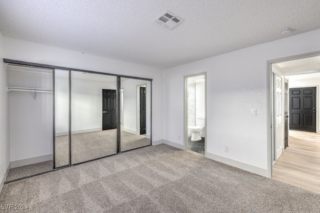 unfurnished bedroom with a textured ceiling, ensuite bathroom, and a closet