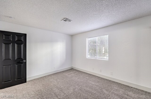 carpeted spare room with a textured ceiling