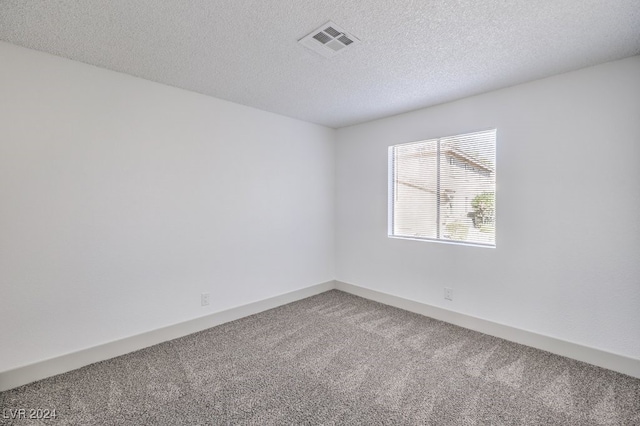 empty room with carpet flooring and a textured ceiling