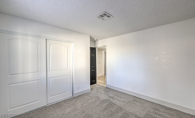 unfurnished bedroom featuring a closet, light colored carpet, and a textured ceiling