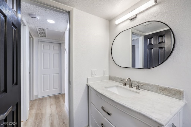 bathroom featuring hardwood / wood-style floors, vanity, and a textured ceiling