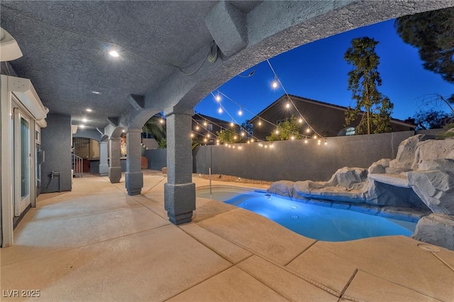 pool at night featuring a patio