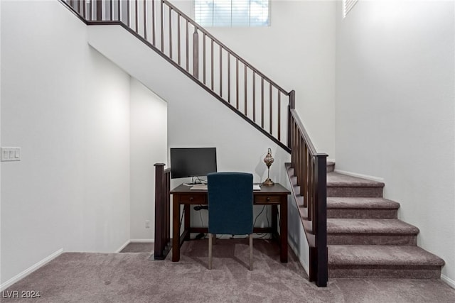 home office with carpet flooring, a wealth of natural light, and a high ceiling