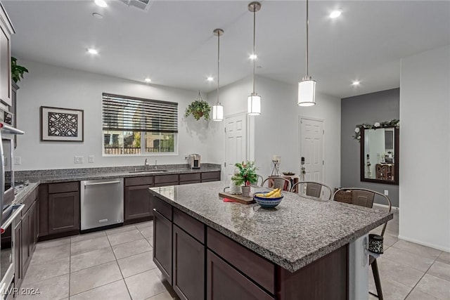 kitchen featuring a breakfast bar, hanging light fixtures, light tile patterned floors, appliances with stainless steel finishes, and a kitchen island