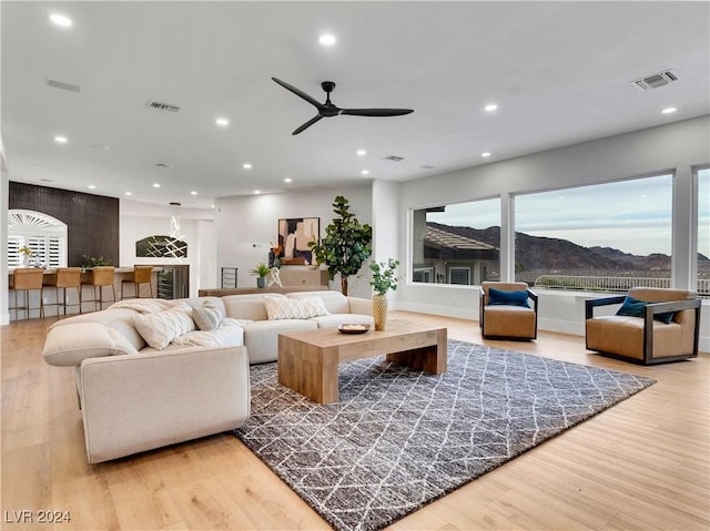 living room with a mountain view, light hardwood / wood-style flooring, and ceiling fan