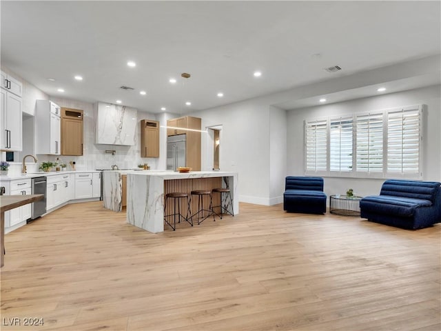 kitchen featuring a center island, a kitchen breakfast bar, light wood-type flooring, appliances with stainless steel finishes, and white cabinetry