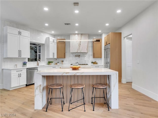 kitchen featuring a center island, white cabinets, light wood-type flooring, and appliances with stainless steel finishes