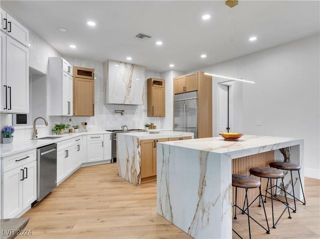 kitchen with white cabinetry, sink, a kitchen island, and high end appliances