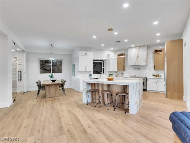 kitchen featuring white cabinets, a center island, light hardwood / wood-style floors, and premium range hood