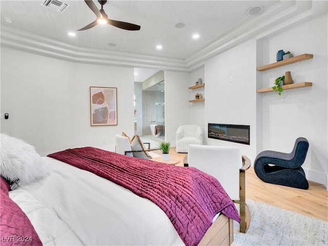 bedroom with a tray ceiling, ceiling fan, ensuite bathroom, and light hardwood / wood-style floors