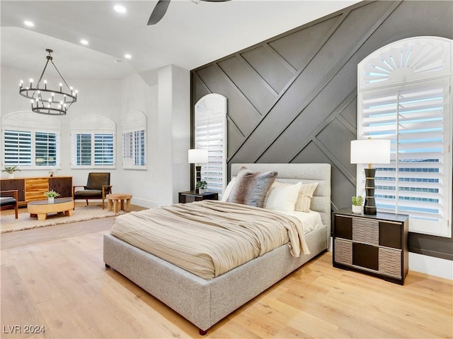 bedroom with ceiling fan with notable chandelier and light wood-type flooring