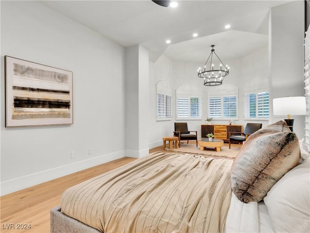 bedroom featuring a chandelier, lofted ceiling, and wood-type flooring