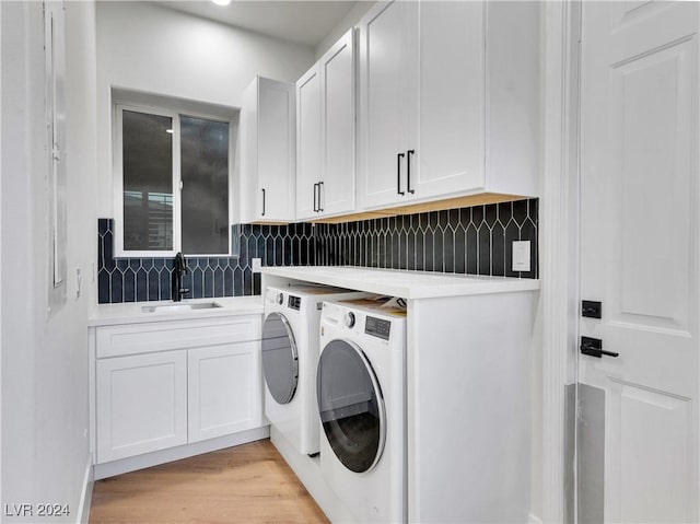 washroom featuring washing machine and clothes dryer, light wood-type flooring, cabinets, and sink