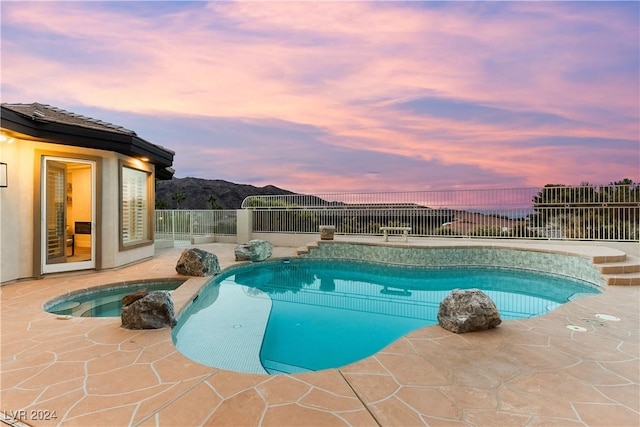 pool at dusk featuring an in ground hot tub