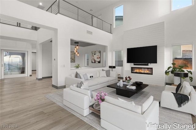 living room with light hardwood / wood-style flooring and a towering ceiling