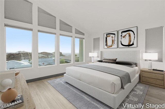 bedroom featuring a mountain view, light hardwood / wood-style floors, and vaulted ceiling