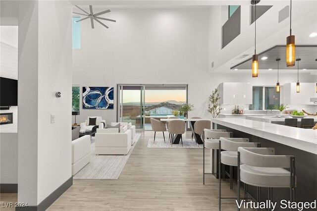 interior space featuring light wood-type flooring, a high ceiling, and ceiling fan