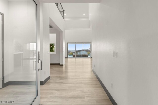 hall with light hardwood / wood-style flooring and a high ceiling