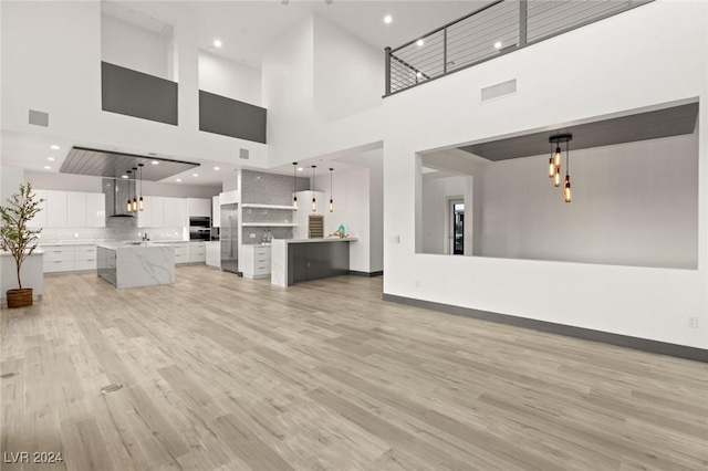 unfurnished living room with a high ceiling and light hardwood / wood-style floors