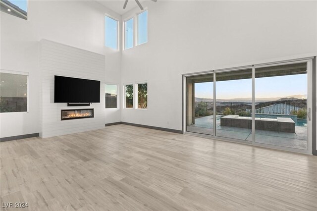 unfurnished living room featuring a mountain view, light hardwood / wood-style flooring, and a towering ceiling