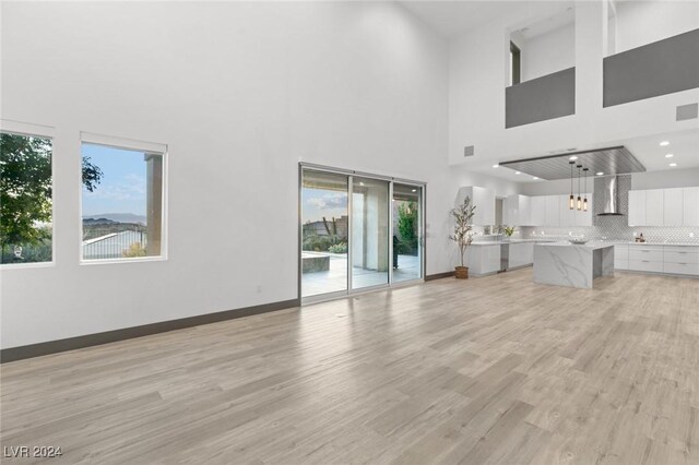 unfurnished living room featuring light wood-type flooring and a high ceiling