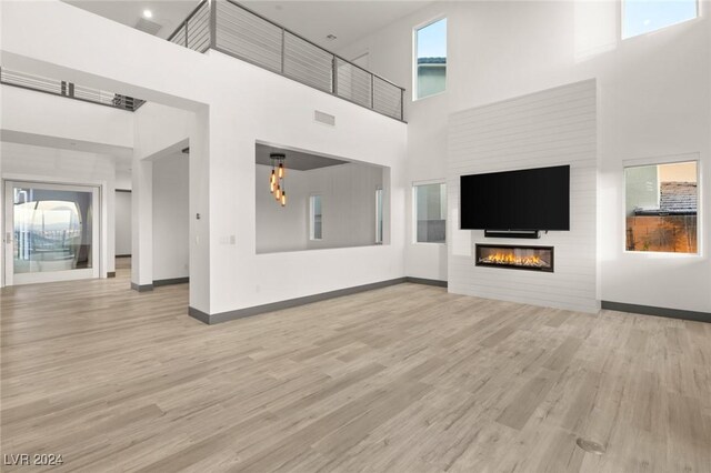 unfurnished living room featuring a high ceiling and light hardwood / wood-style flooring