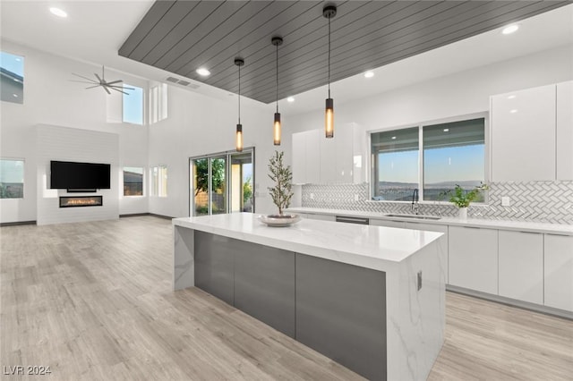 kitchen with sink, white cabinetry, a center island, and hanging light fixtures