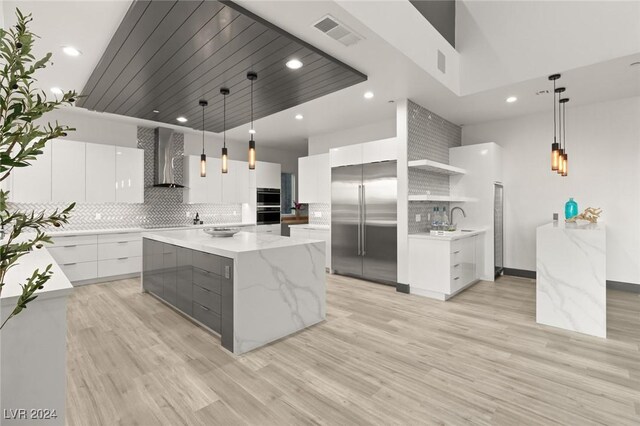 kitchen with pendant lighting, white cabinetry, stainless steel built in refrigerator, and a large island