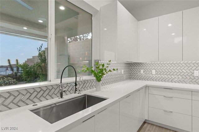 kitchen featuring sink, backsplash, white cabinets, and plenty of natural light