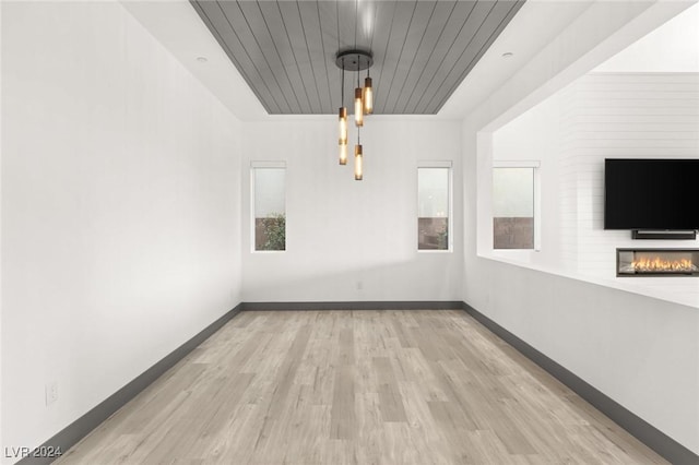 unfurnished dining area featuring a fireplace, light hardwood / wood-style flooring, and wood ceiling