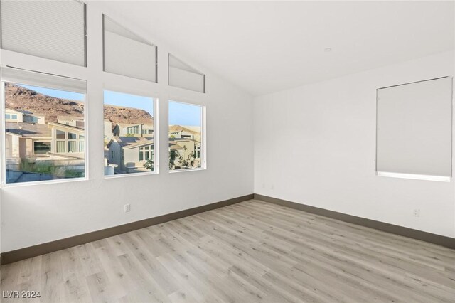 unfurnished room featuring light hardwood / wood-style floors and high vaulted ceiling