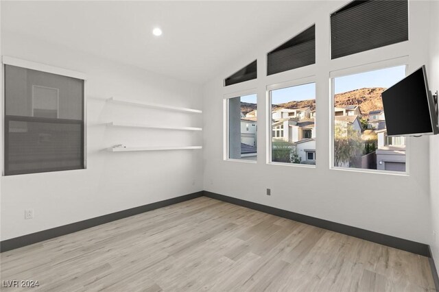 spare room with light hardwood / wood-style flooring and lofted ceiling