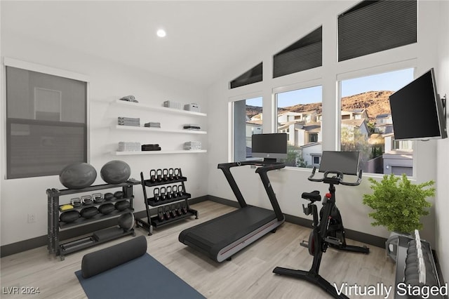 exercise room featuring light hardwood / wood-style flooring and lofted ceiling