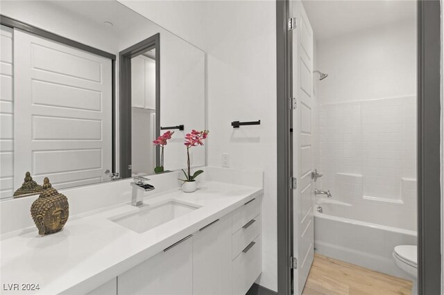 full bathroom featuring shower / bathtub combination, hardwood / wood-style floors, toilet, and vanity