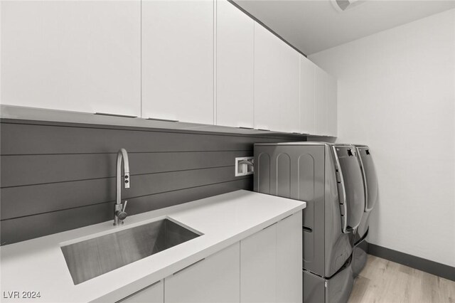 washroom featuring sink, separate washer and dryer, cabinets, and light wood-type flooring