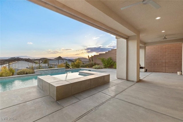 pool at dusk featuring pool water feature, an in ground hot tub, a patio, and ceiling fan