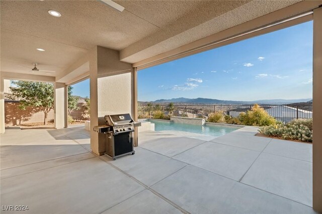 view of patio with a fenced in pool, a mountain view, a grill, and ceiling fan