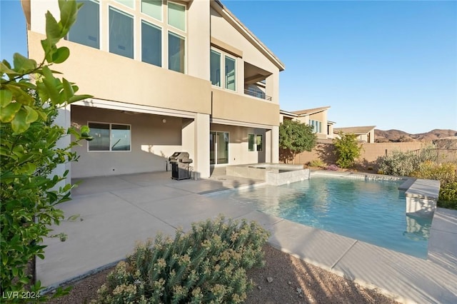 view of swimming pool featuring a mountain view, an in ground hot tub, a patio area, and area for grilling