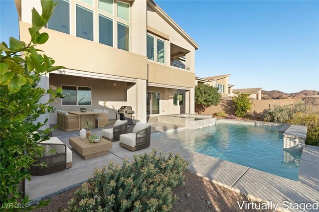 view of pool with a mountain view, a patio area, an outdoor living space, and a hot tub