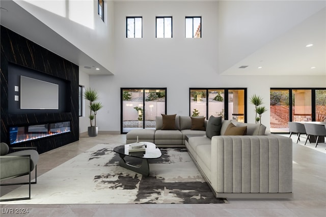 living room with a fireplace, a healthy amount of sunlight, and a high ceiling