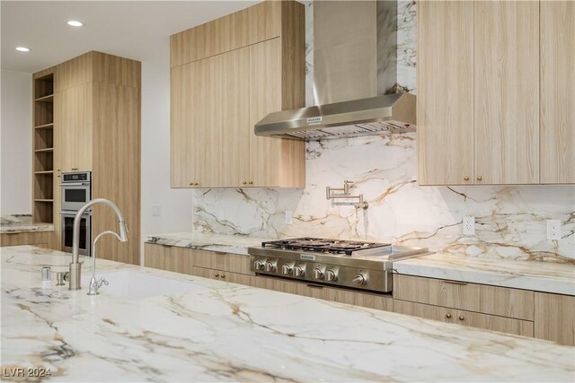 kitchen featuring light brown cabinets, sink, wall chimney exhaust hood, light stone countertops, and stainless steel appliances