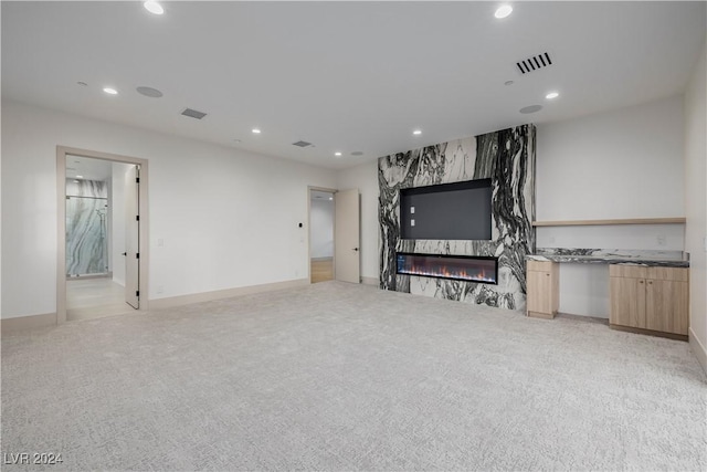 unfurnished living room with light carpet and a fireplace