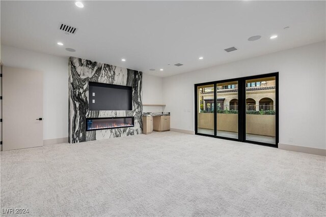 interior space with light carpet and a high end fireplace