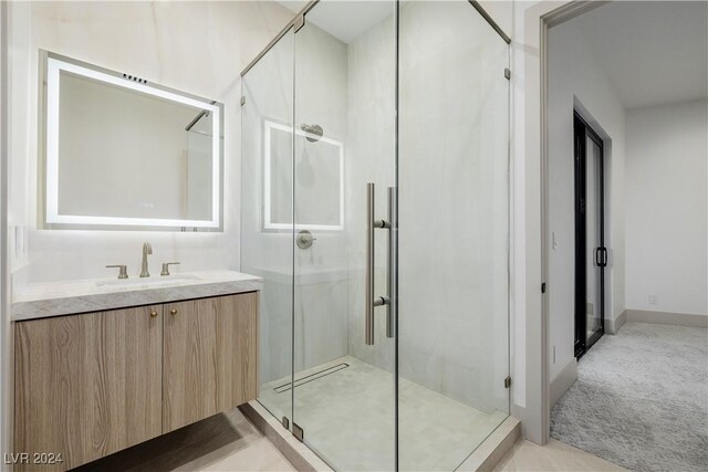 bathroom featuring a shower with door and vanity