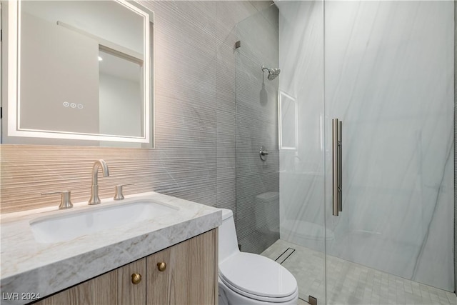 bathroom featuring walk in shower, vanity, tile walls, and toilet