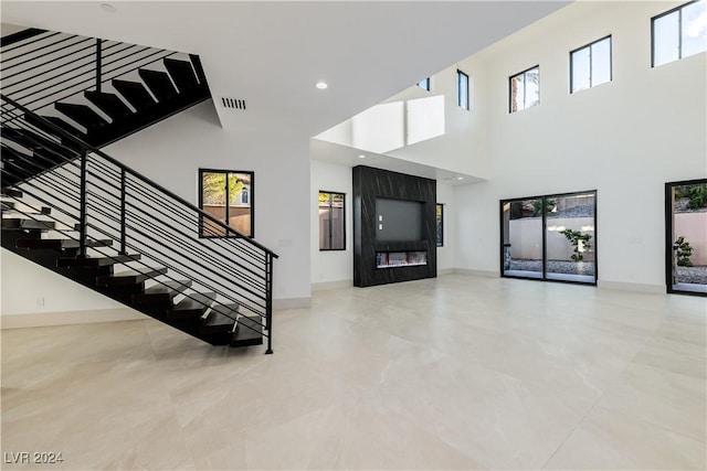 staircase with a towering ceiling and concrete flooring