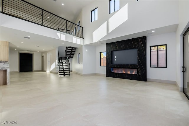 unfurnished living room with a fireplace and a towering ceiling