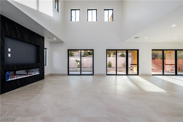 unfurnished living room featuring a healthy amount of sunlight, a fireplace, and a high ceiling