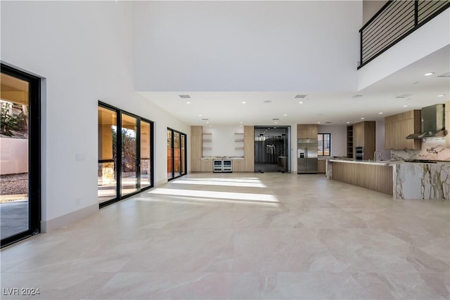 unfurnished living room with a towering ceiling and plenty of natural light